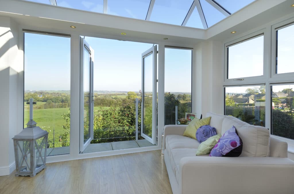 French doors located within a conservatory leading out onto a patio in the countryside.