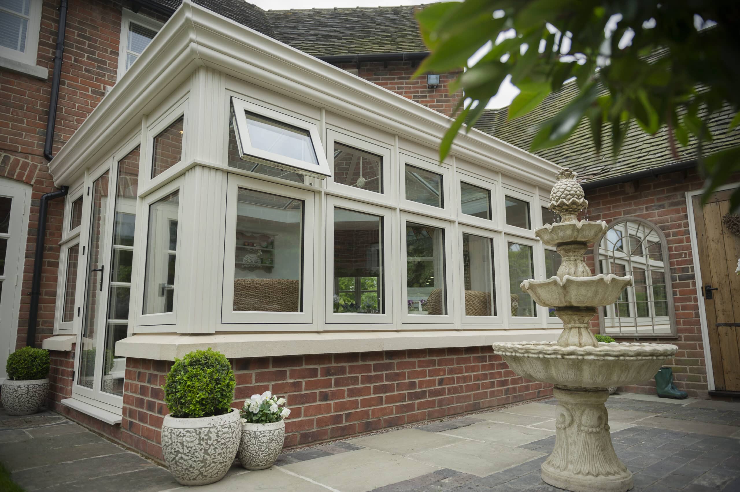 The Residence Collection R9 flush windows in Clotted Cream in conservatory, with patio and water feature