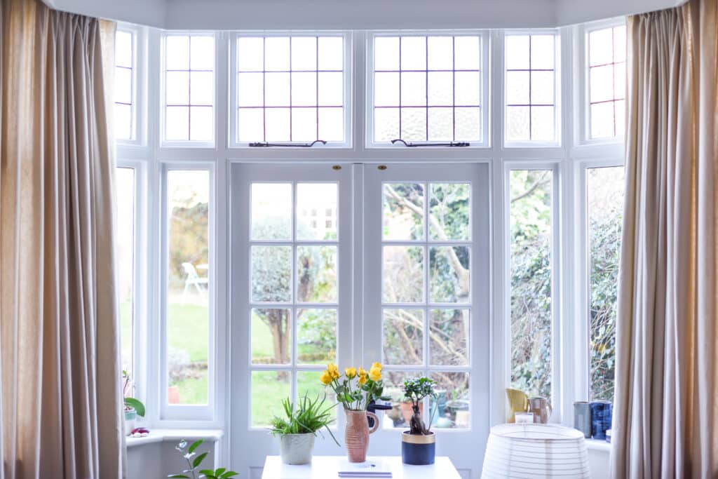 front on view of beige curtains hanging within a bay window